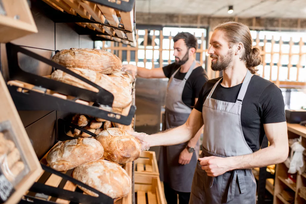 two men in aprons are working in a bakery.